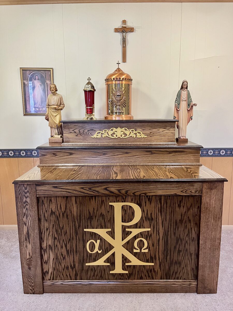 Custom oak altar with gold Chi Rho and Alpha Omega symbols, installed in a chapel with tabernacle and crucifix