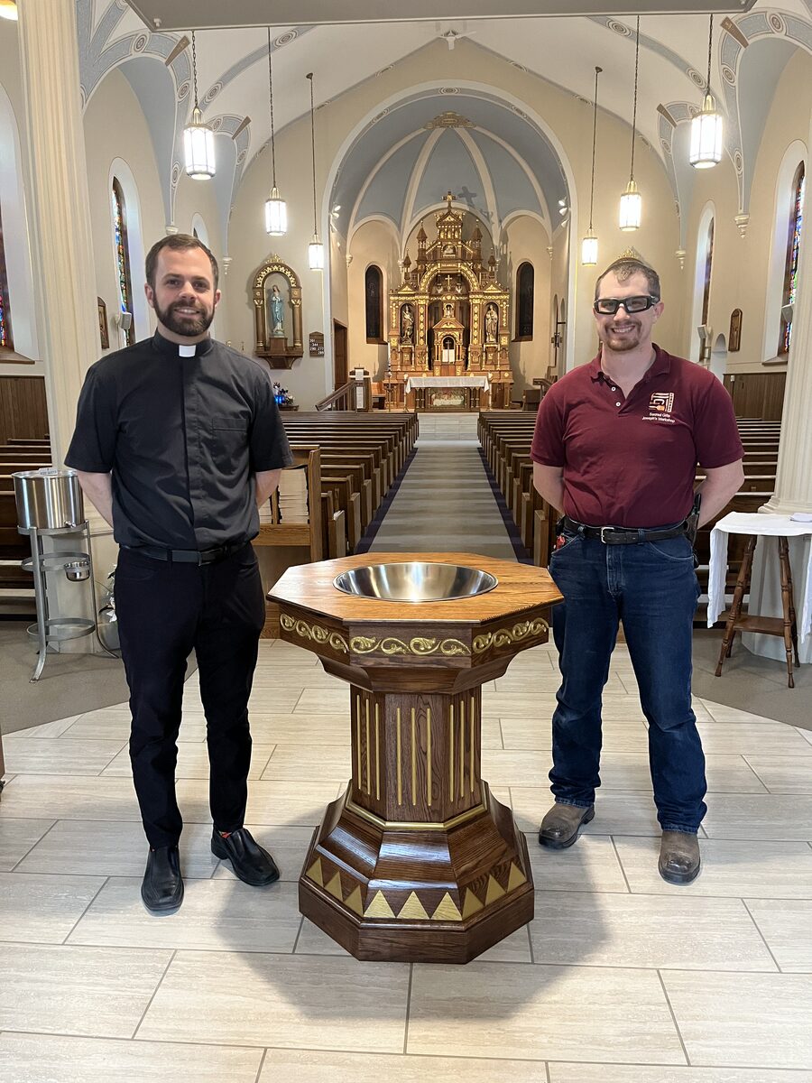 Mark from Joseph's Workshop standing with a priest next to a custom baptismal font installed in a Catholic church