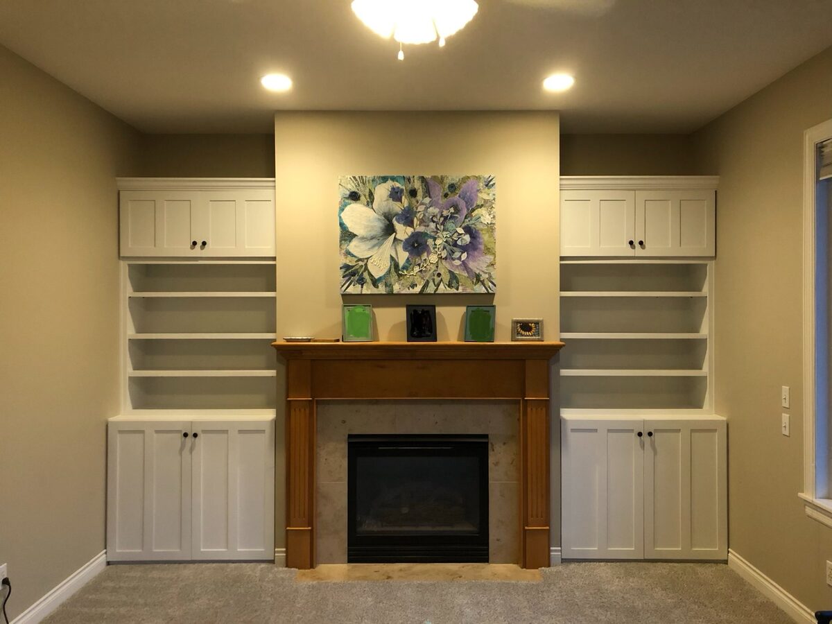 Custom white shaker built-in cabinetry with shelving around a living room fireplace