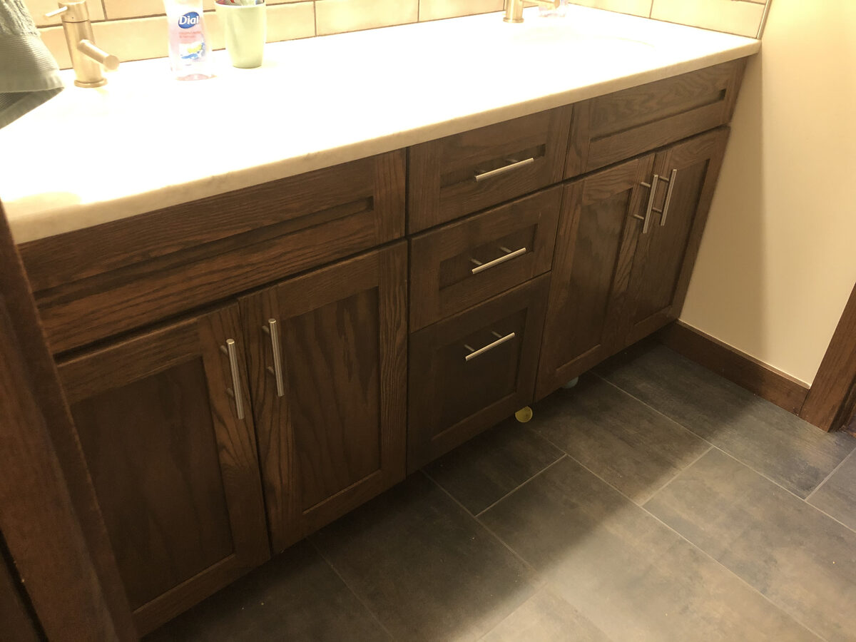 Custom dark oak bathroom vanity with white countertop and brushed nickel hardware