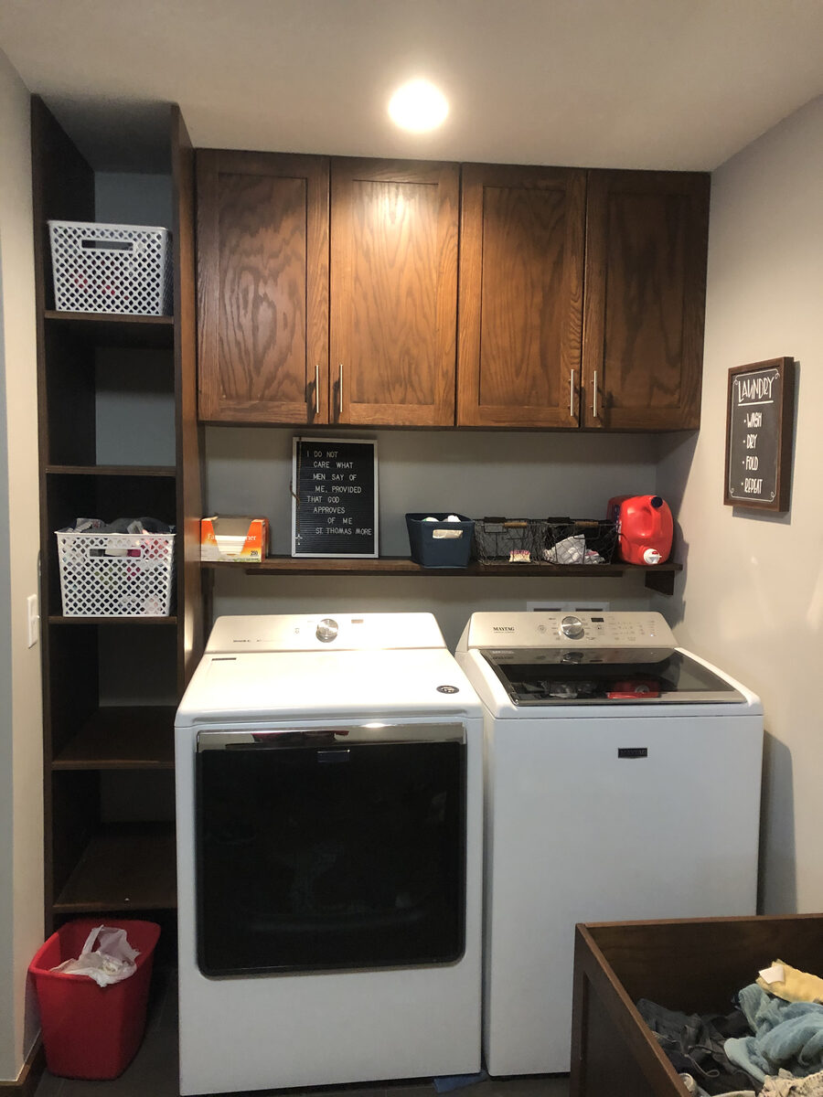 Custom oak laundry room cabinetry with upper cabinets and open shelving