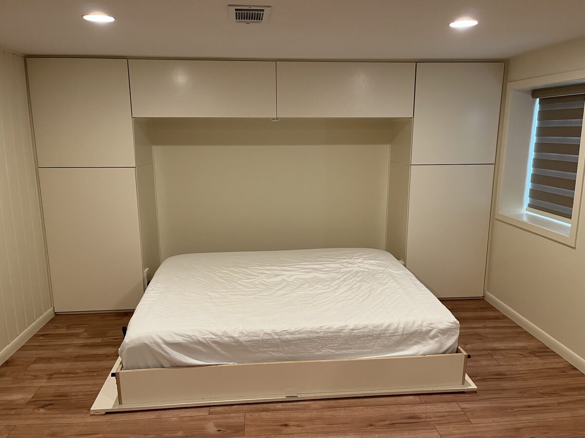Custom Murphy bed with built-in wall cabinetry and storage in a finished basement