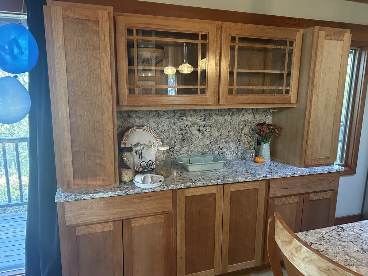Custom cherry buffet cabinet with glass-front doors, Cambria countertop and backsplash, pendant lighting
