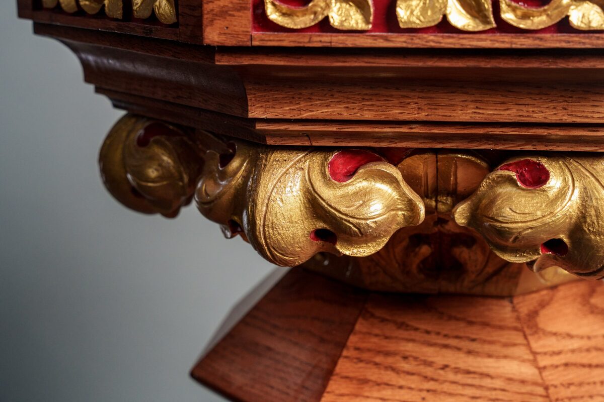 Hand-carved gold acanthus leaf scrollwork on baptismal font pedestal