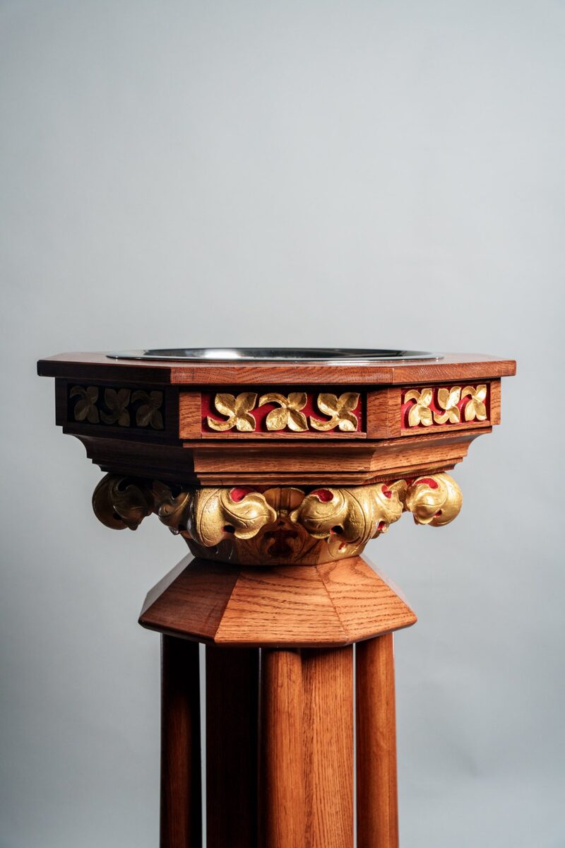 Custom handcrafted baptismal font with gold leaf detailing and ornate carved acanthus leaves